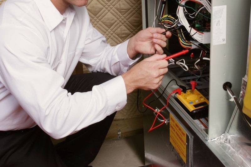 A technician inspecting and diagnosing the internals of a furnace